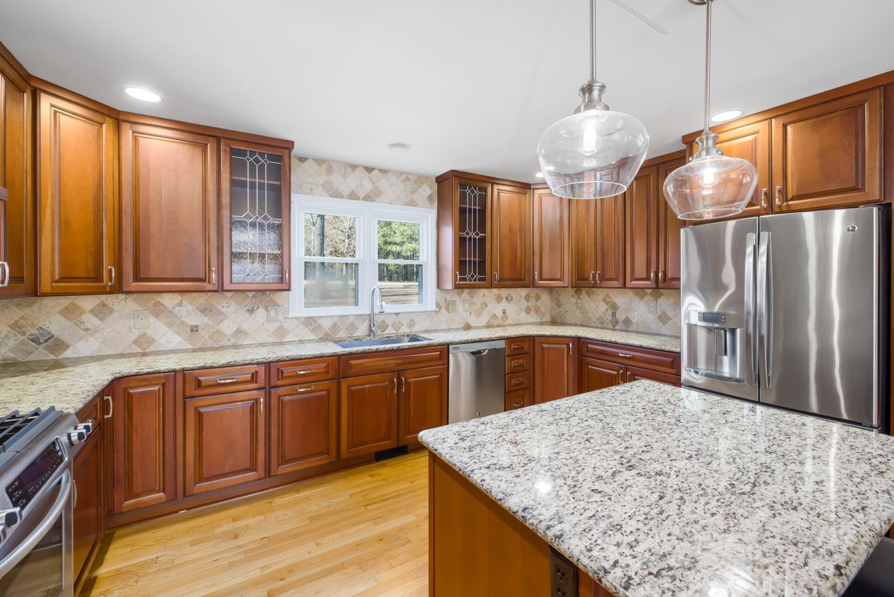 Spacious kitchen with wooden cabinets, granite island, and stainless steel appliances.